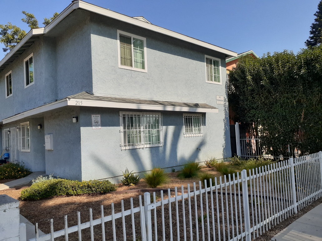 A grey house with a white picket fence in front.